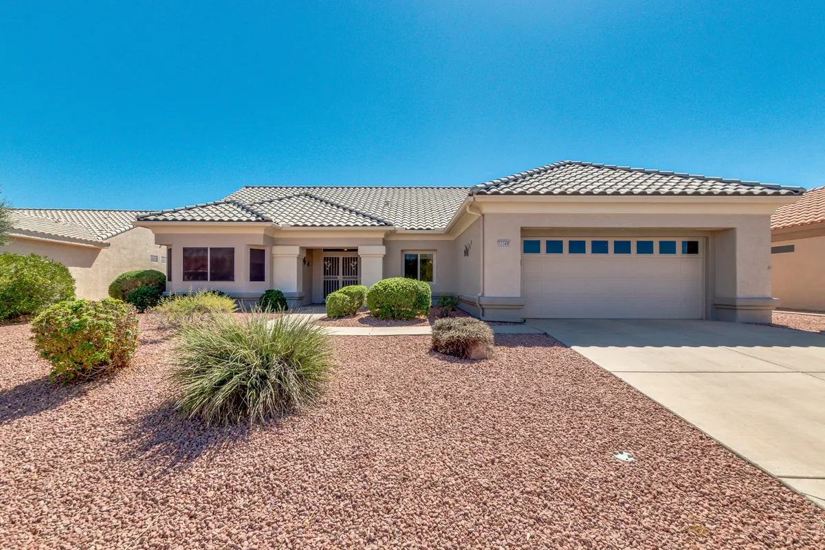 An exterior view showcasing a spacious driveway, textured roof tiles, and manicured landscaping. The setting hints at possibilities for outdoor barbecues, family gatherings, and sunny afternoons spent with friends.