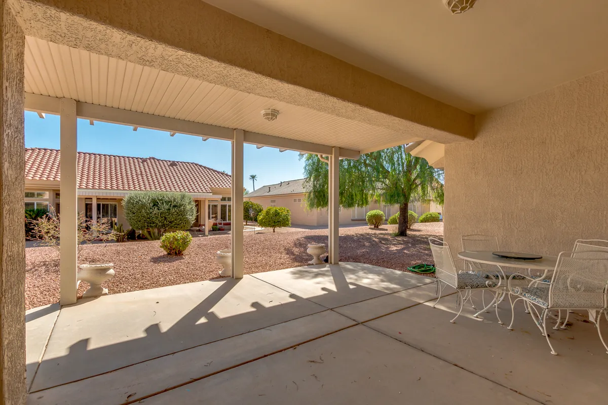A tranquil covered patio area that opens onto a beautifully landscaped garden, with decorative stone planters and space for dining or lounging. The serene setting suggests morning breakfasts, family celebrations, or peaceful evenings under the stars, highlighting the seamless indoor-outdoor flow.
