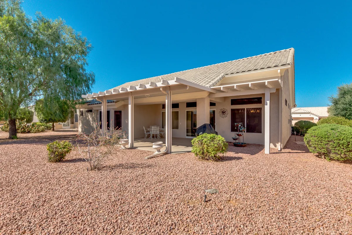 A welcoming covered porch framed by lush landscaping and a rock garden. The porch offers comfortable seating, perfect for relaxing outdoors. The scene evokes the enjoyment of Arizona’s year-round sunshine and tranquil neighborhood living.
